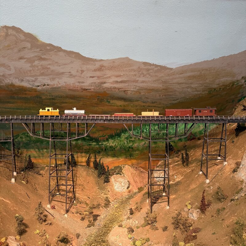 Freight train crossing a tall trestle above a rocky canyon