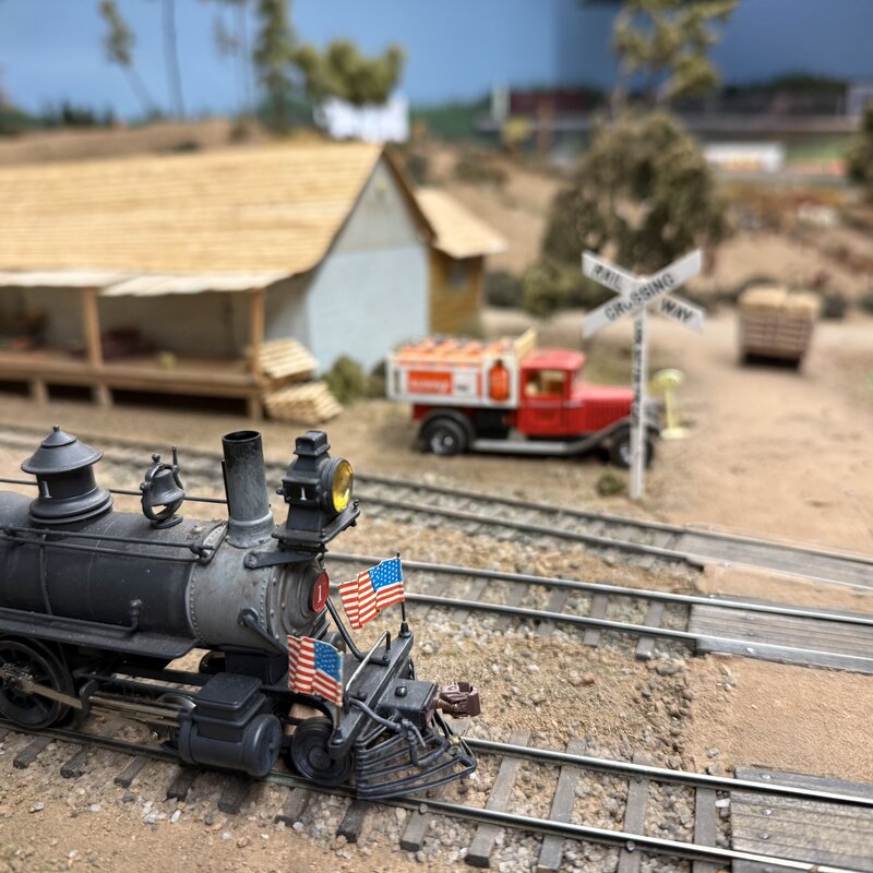Close-up of a steam locomotive's headlamp, smokestack, and American flags