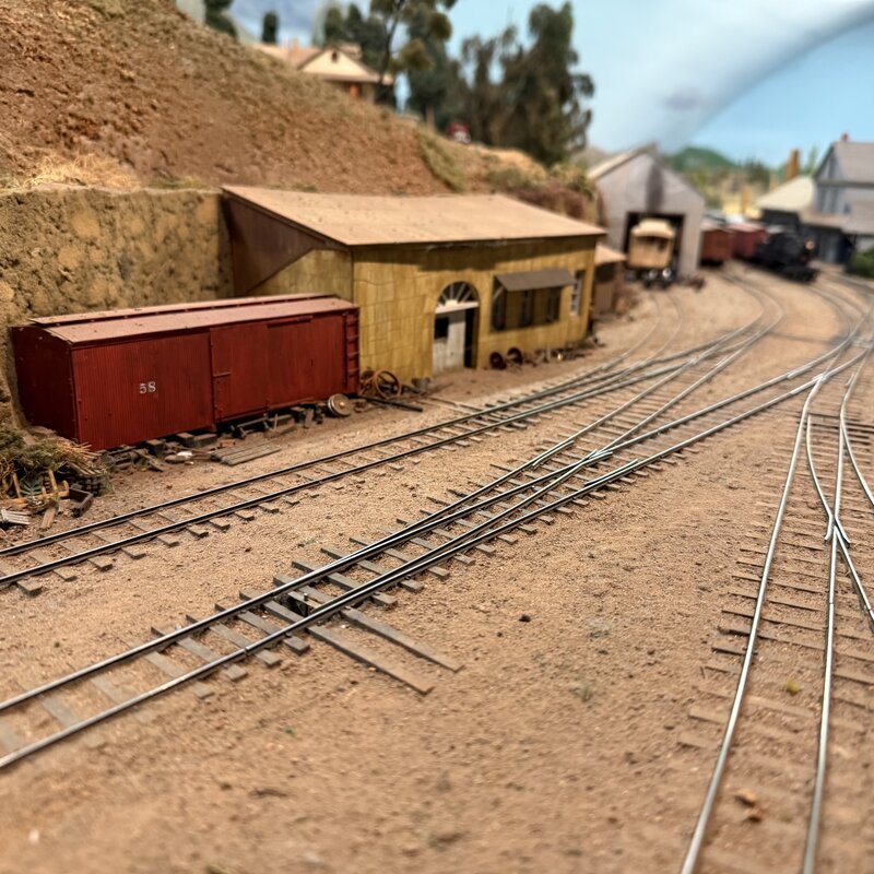 Red boxcar beside a wooden yard building and converging tracks