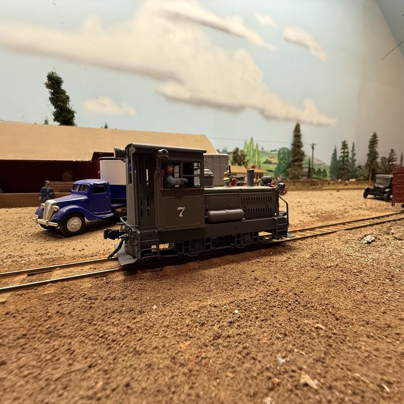 Small model locomotive numbered 7 beside a blue truck