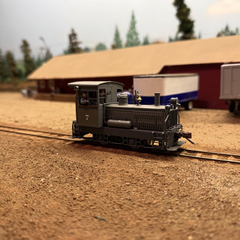 Side view of model locomotive No. 7 in front of a freight shed
