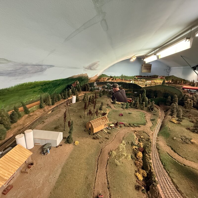 Volunteer working inside the layout among wooded hills and unfinished scenery
