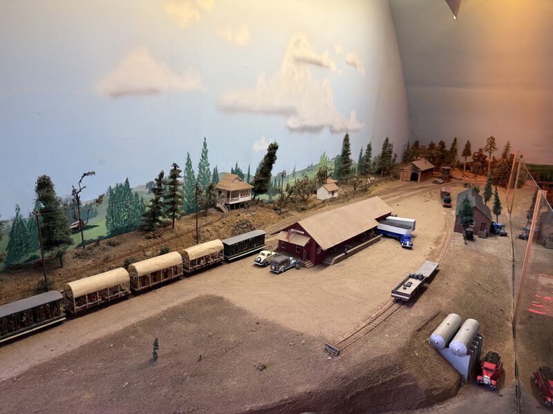 Overhead layout view showing buildings, track, and rolling stock with mountain backdrop